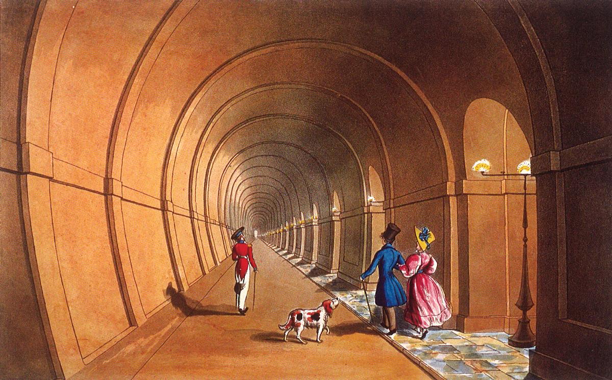 Pedestrians and a dog walking through the Thames Tunnel